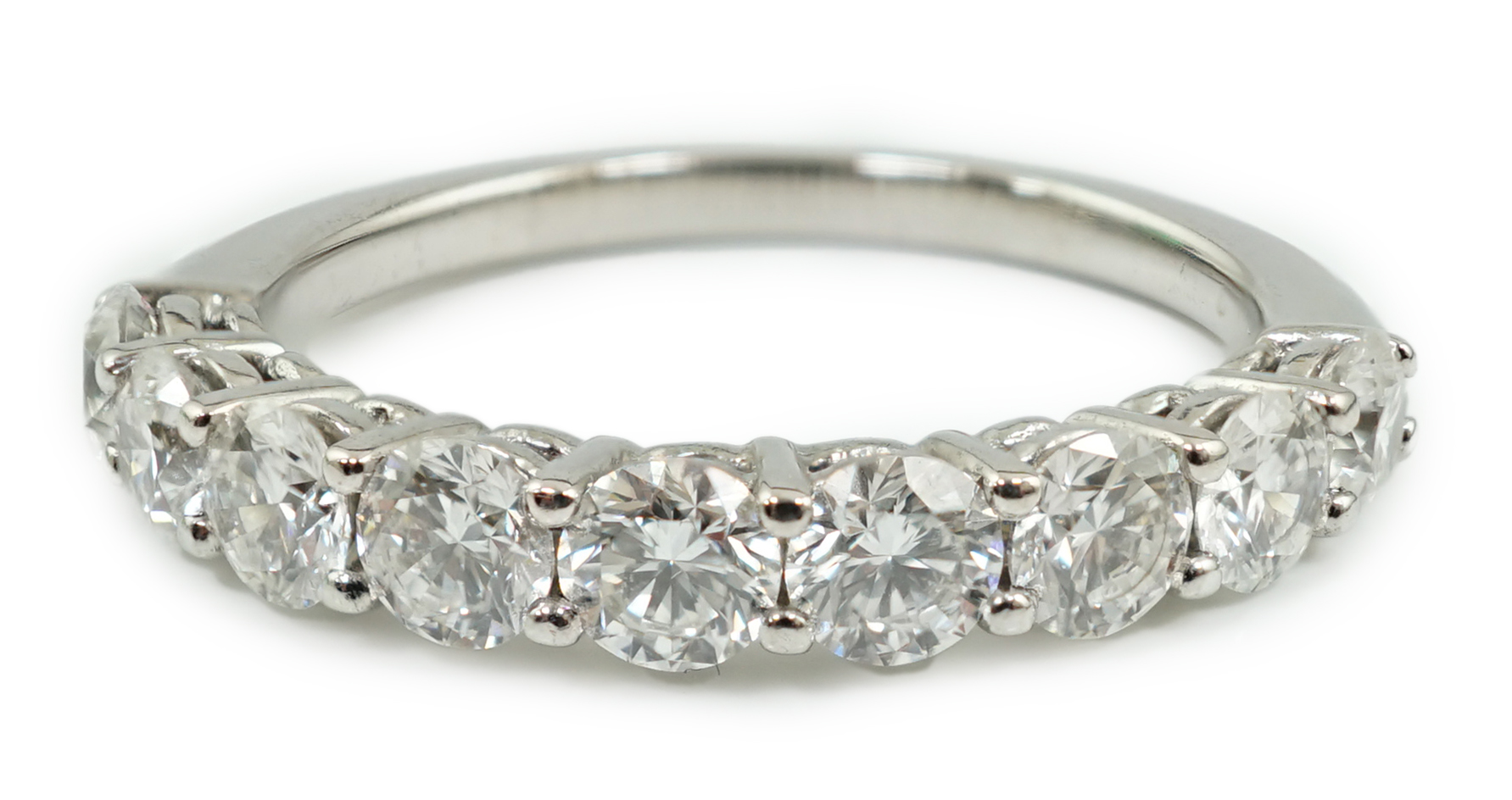 A white gold and nine stone set round brilliant cut diamond set half hoop ring